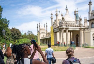 A student taking a photo of Brighton Pavilion from the outside on a clear sunny day
