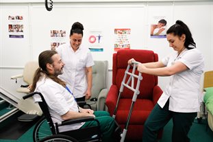 Occupational therapy students demonstrating safe movement with apprentice Ian