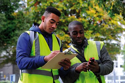 Two students in hi-viz comparing readings outside