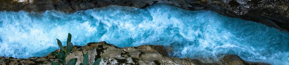 Birds eye view down both sides of rocky chasm with fast moving blue river below. Courtesy Jonas Gerg and Unsplash