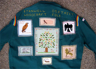 Dark blue shirt with Stanwell District Woodcraft Folk sewn on and various animal and nature badges