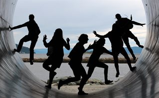 Silhouette of six adults playing at the mouth of a tunnel with the sea in the distance. Courtesy Maike und Björn Bröskamp from Pixabay