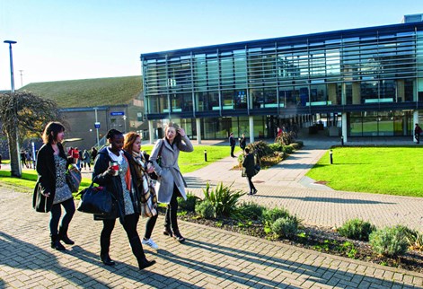 Group of students walking past Checkland Building on Falmer campus