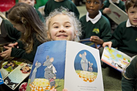 Close up of primary school girl holding up a book
