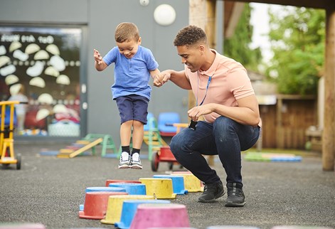 Male teacher and child playing on stepping blocks