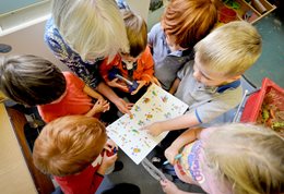 A group of children pointing at a picture in a nursery