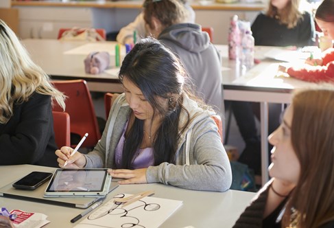 Art PGCE trainee teacher in classroom drawing on tablet