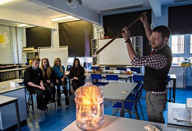 Controlled chemical fire experiment at the front of a secondary school chemistry classroom