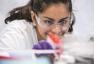 Close up of a pharmacy student in white coat and safety glasses