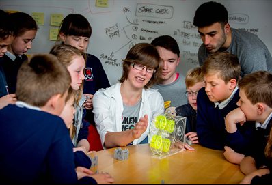 A group of school children discussing the 3D printing process with an adult