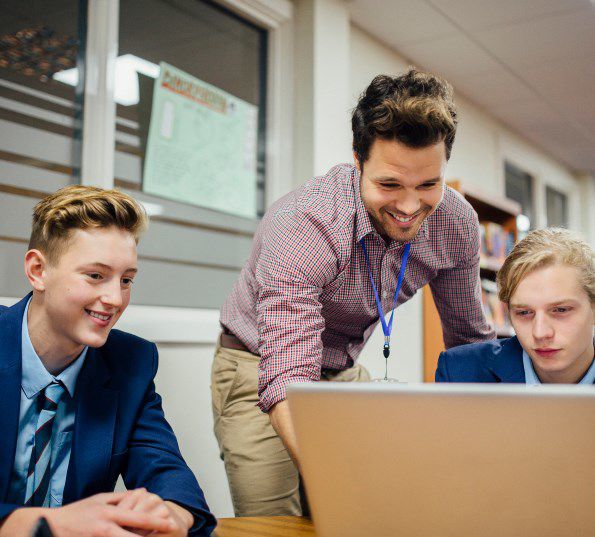 Student helping pupils at a computer