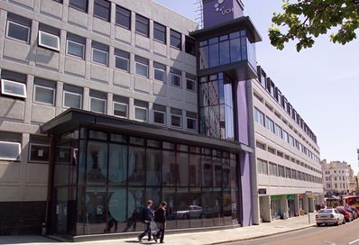 Two people walking past the outside of the University Centre Hastings, 2003