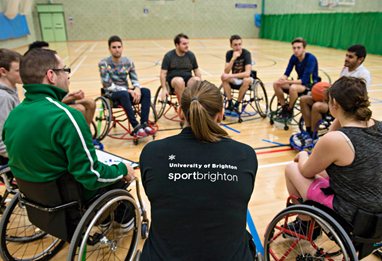 A circle of people in wheelchairs preparing to play a game with a ball