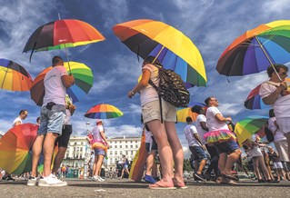 A group of people holding up rainbow umbrellas