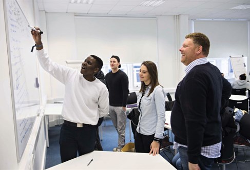 Students and staff looking at writing on a whiteboard