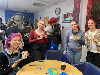 Students holding mugs they have decorated