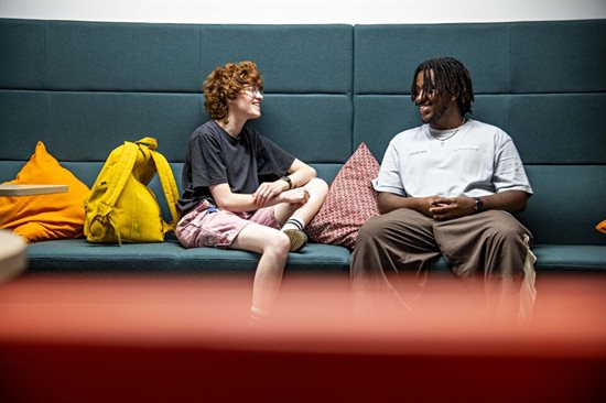 Two students sitting on a sofa and talking