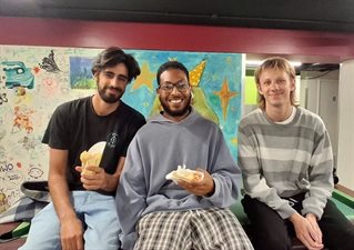Three students sitting on a pool table