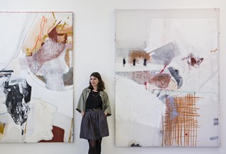 Student standing between two large abstract paintings