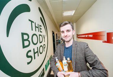 Man holding plastic bottles next to the Body Shop logo