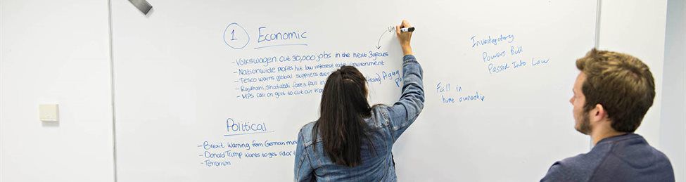 Student writing on whiteboard in lecture
