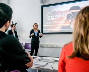 a woman in a suit presenting a business plan in class