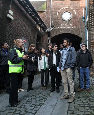 Student group stands with business managing presenters at brewery business Shepherd Neame