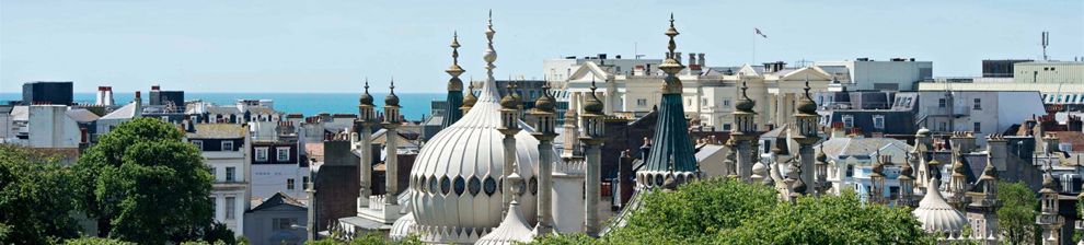 Brighton rooftops with domes of Royal Brighton Pavilion, blue sky.