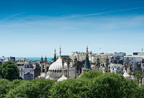 Brighton rooftops with domes of Royal Brighton Pavilion, blue sky.