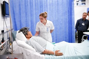 nursing student caring for mannequin under supervision