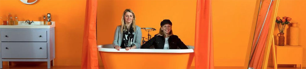Hannah Lane with colleague in bathtub with orange backdrop