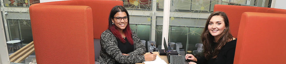 Two students on placement in an orange booth