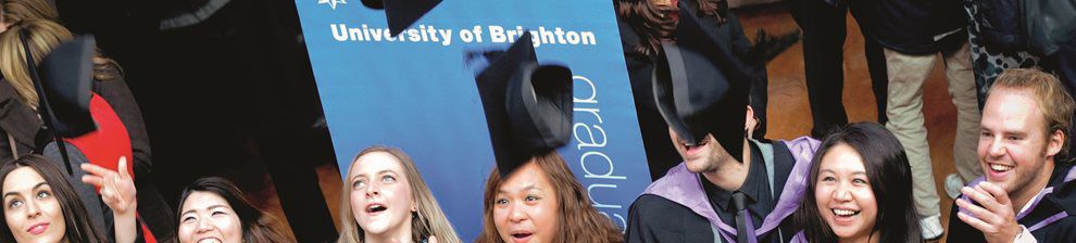 Students in robes celebrating at awards ceremony, throwing their mortarboard in the air