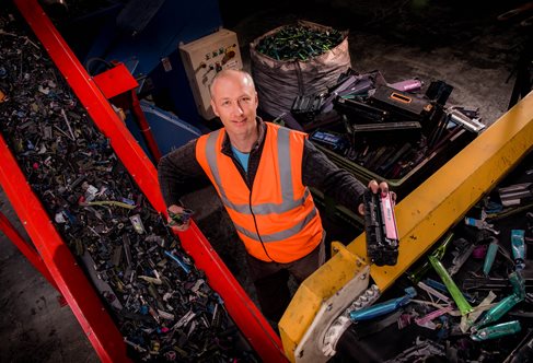 Worker from BCMY standing amongst ink cartridges being recycled