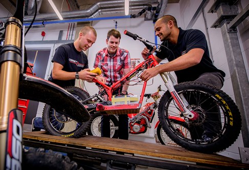 Three people working on an OSET Bike