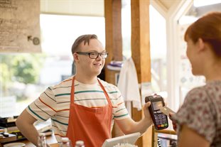 A woman makes a purchase in a cafe from a worker