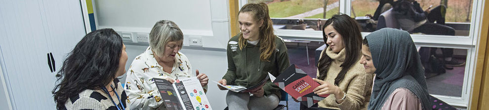 Careers advisers and students in a circle discussing a skills workbook