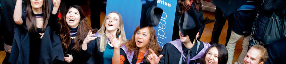 Graduates in gowns throwing their mortar boards in the air