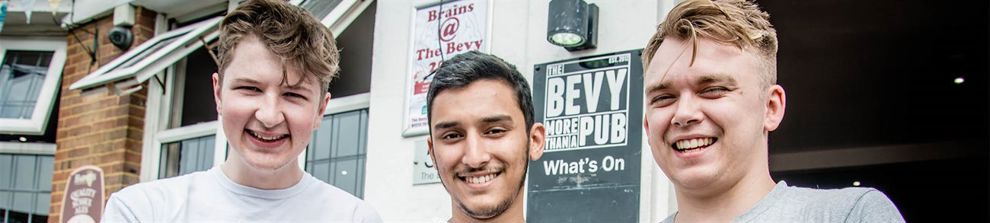 Three students volunteers with paint and rollers outside the Bevy pub