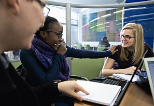 A staff member helping two students with their applications