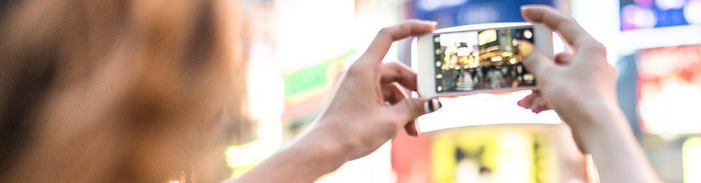 Two hands holding a mobile device, with a blurred screen