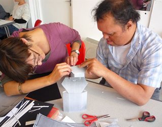 Student and teacher co-operating on a paper sculpture