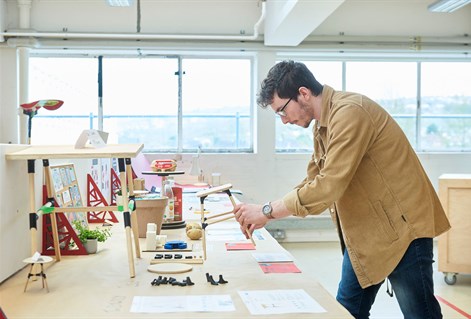 Student looking at a wooden prototype on work bench