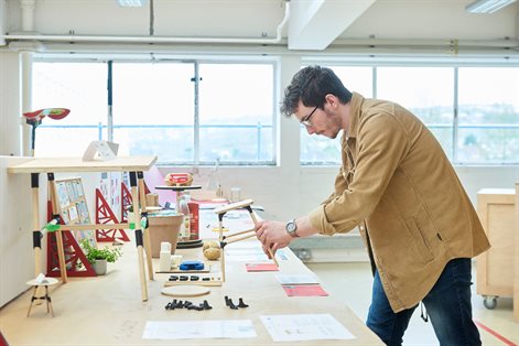 Student looking at a wooden prototype on work bench