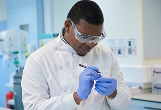 Biomedical science male student marking up a test tube containing a plasma sample