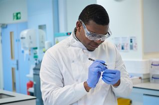 Biomedical science male student marking up a test tube containing a plasma sample