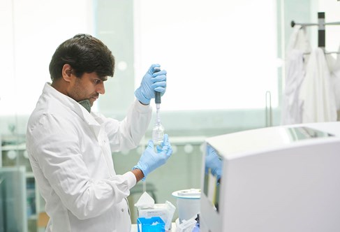 PG student in the lab focusing on a bottle and pipette