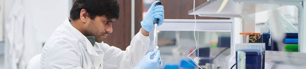 Scientist in a white lab coat testing samples in a lab