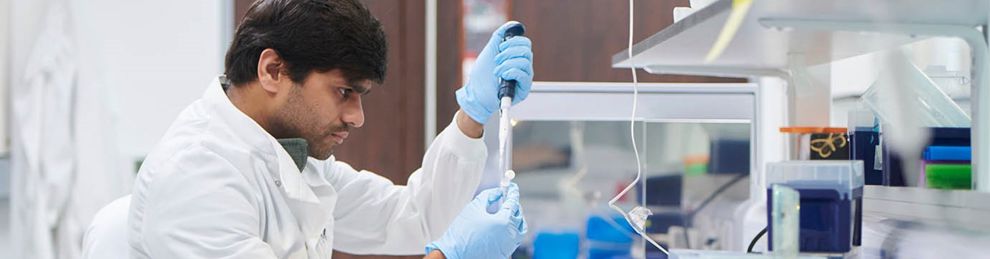 Scientist in a white lab coat testing samples in a lab