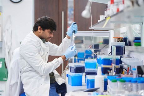 Scientist in a white lab coat testing samples in a lab